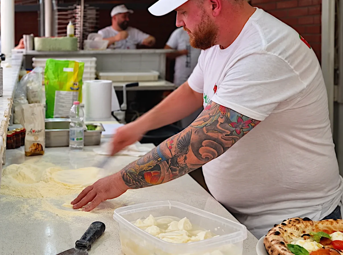 Pizzaiolo al lavoro con mozzarella pronta per la pizza